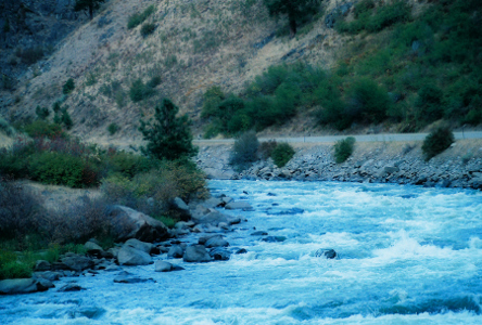 [Lots of rocks and whitewash in this bend of the river near the road at the bottom of a tall hillside.]